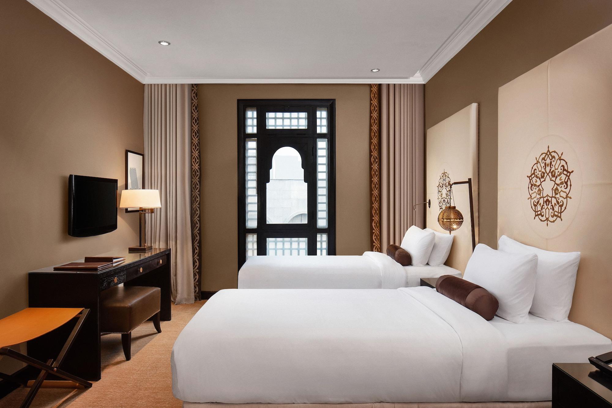 Sofitel Shahd Al Madinah Hotel Medina Exterior photo The photo shows a well-decorated hotel room featuring two single beds with white bedding. The walls are a warm beige color, and there are decorative elements such as patterned wall panels and a large window with an elegant design. In the room, there 