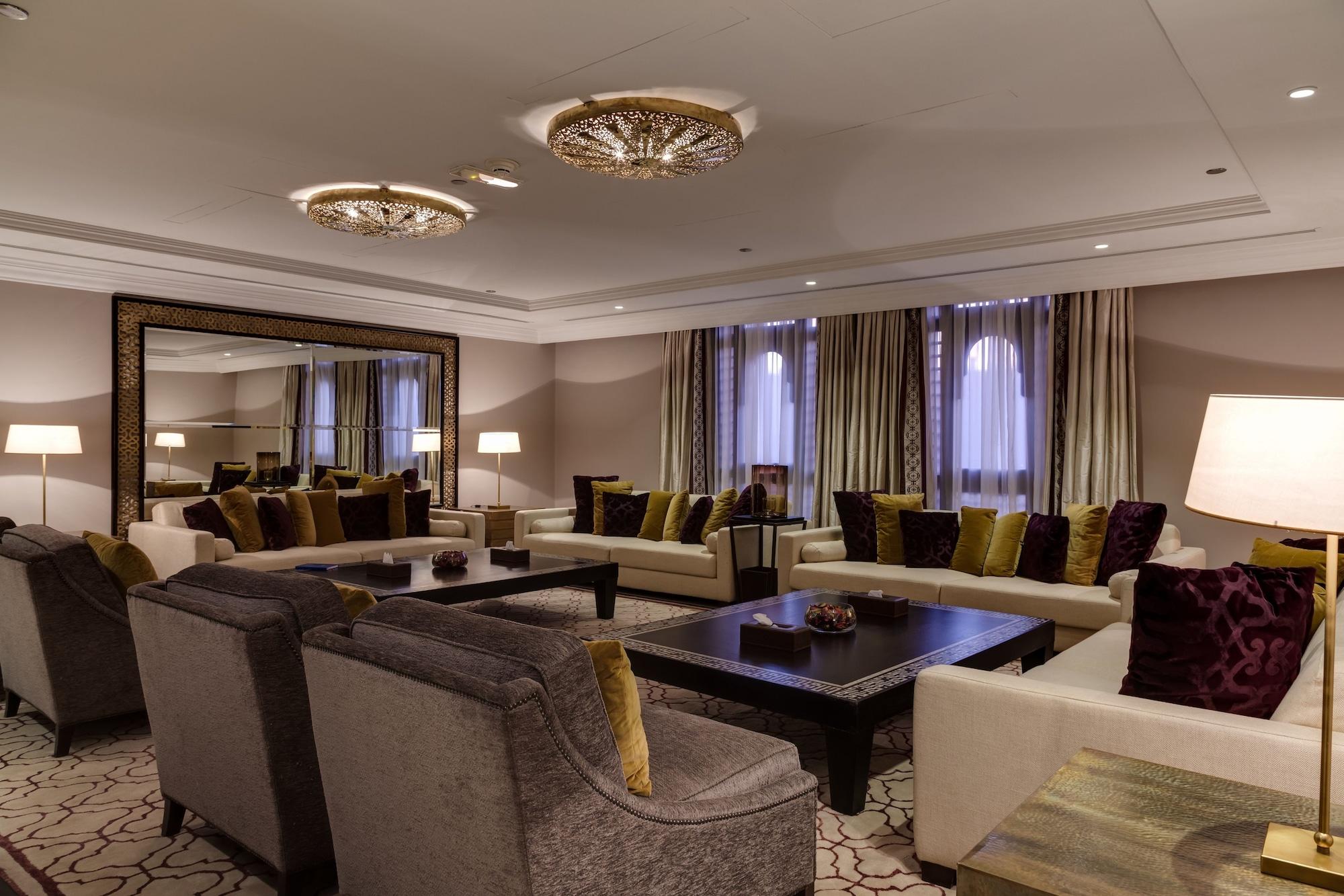Sofitel Shahd Al Madinah Hotel Medina Exterior photo The photo showcases an elegant living room designed with a sophisticated aesthetic. It features a mix of plush seating arrangements, including gray sofas and armchairs adorned with colorful cushions in shades of green and purple. A large, dark coffee