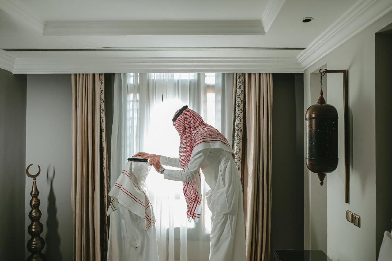 Sofitel Shahd Al Madinah Hotel Medina Exterior photo The photo shows two individuals dressed in traditional clothing, commonly associated with Arabian culture. One person is standing and wearing a headscarf, while the other person is seated or positioned at a lower height, potentially wearing a similar