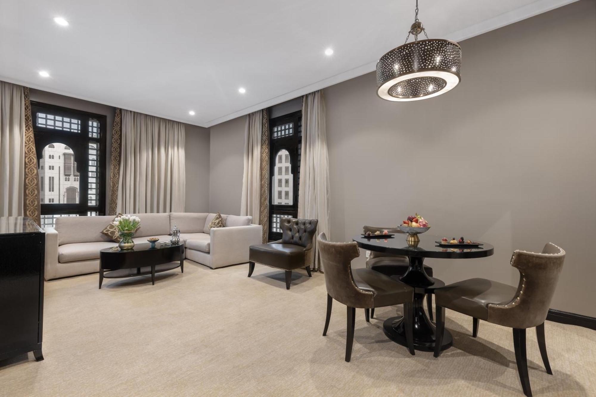 Sofitel Shahd Al Madinah Hotel Medina Exterior photo The photo showcases a modern and elegantly designed living space. It features a light-colored sofa arranged against a wall, complemented by a round dining table with stylish chairs. A small coffee table sits in front of the sofa, and there's a decora