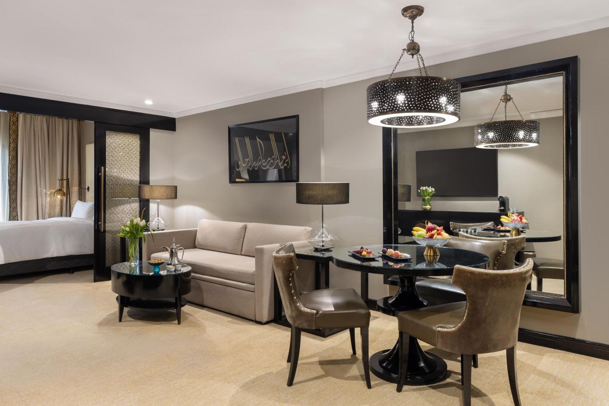 Sofitel Shahd Al Madinah Hotel Medina Exterior photo The photo shows a stylish hotel or apartment room designed for comfort and elegance. 

- On the left, there's a light-colored sofa paired with a round coffee table.
- Adjacent to the sofa, there are two upholstered chairs, creating a cozy seating are