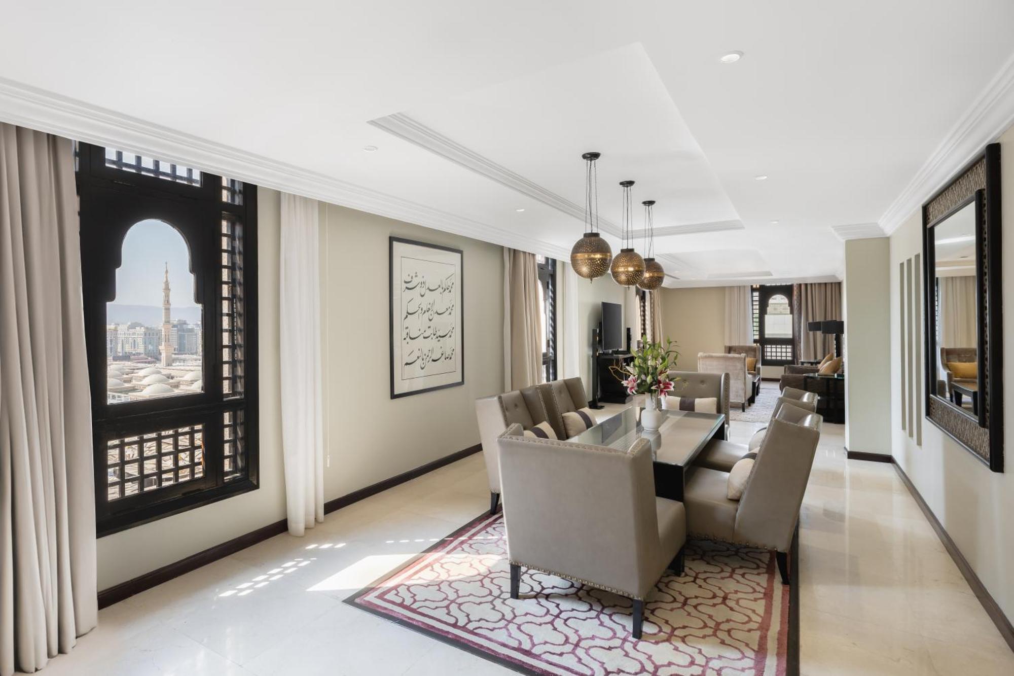 Sofitel Shahd Al Madinah Hotel Medina Exterior photo The photo shows a spacious and elegantly designed interior of a living or dining area. The room features a long table surrounded by several plush chairs, suggesting a space for dining or gatherings. 

Large, ornate windows allow natural light to floo