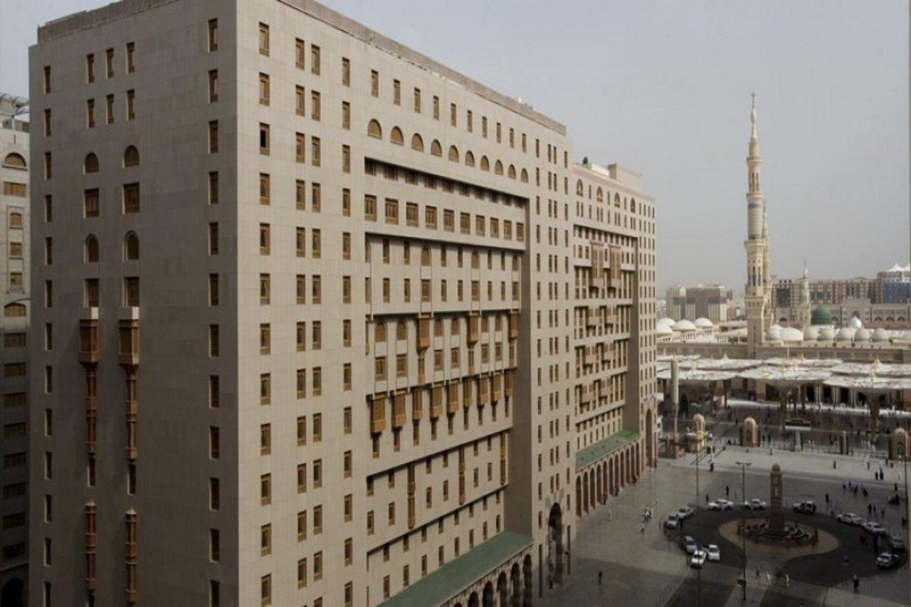 Sofitel Shahd Al Madinah Hotel Medina Exterior photo The photo shows a large modern building with a facade that features numerous windows and architectural detailing. It is situated in an urban setting, with another prominent structure, likely a mosque or minaret, visible in the background. The surroun